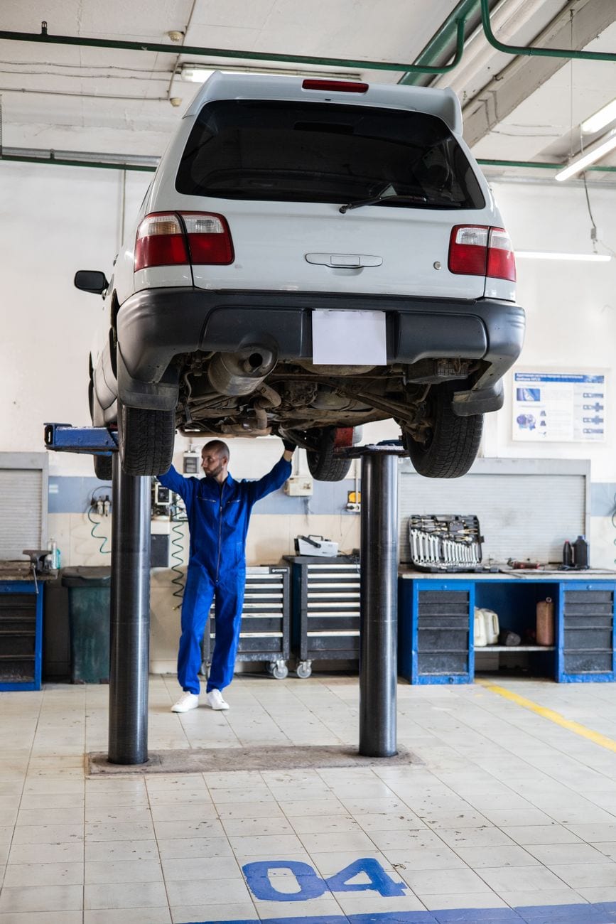 Mechanic inspecting a vehicle on a lift in an auto repair shop
